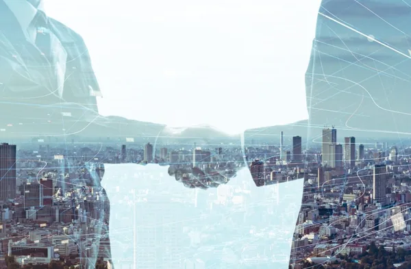 Two people shaking hands with a cityscape and digital network overlay, symbolizing strategic partnerships and collaboration in modern recruitment.