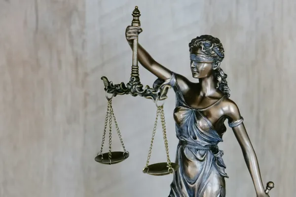 A bronze statue of Lady Justice holding a balance scale, symbolizing fairness and legal compliance in employer practices.