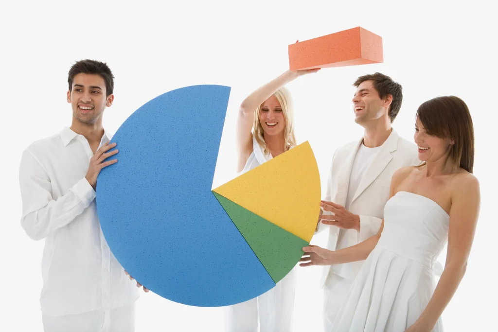 A group of cheerful data scientists in white attire holding and assembling colorful pieces of a large 3D pie chart