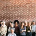 Group of diverse people standing together against a brick wall, representing a tech community.