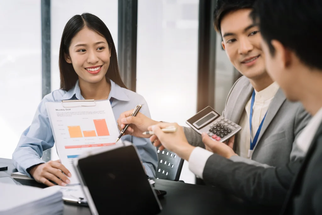 Asian business professionals discussing ESG investment strategies with charts and calculator