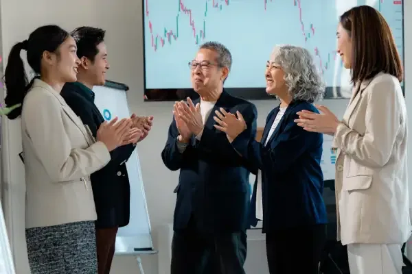 Asian business team applauding successful ESG investment results during a financial meeting.