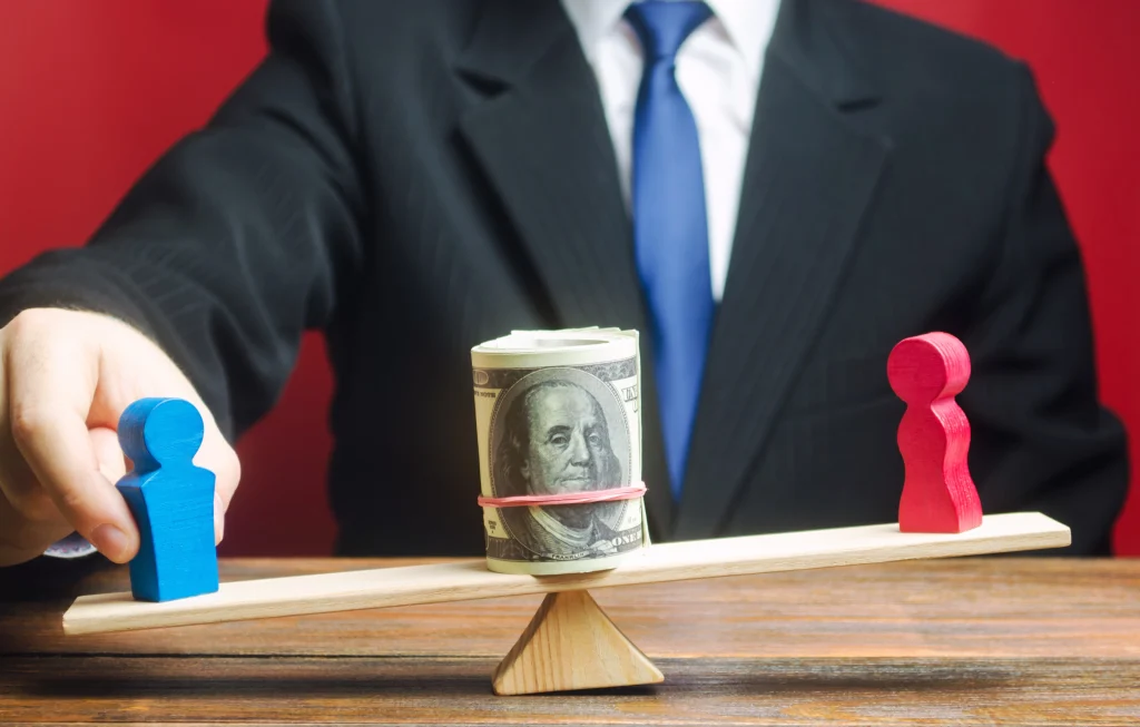 Outsourcing bookkeeping and taxation illustrated by a businessman balancing male and female figures with a roll of cash between them on a seesaw.
